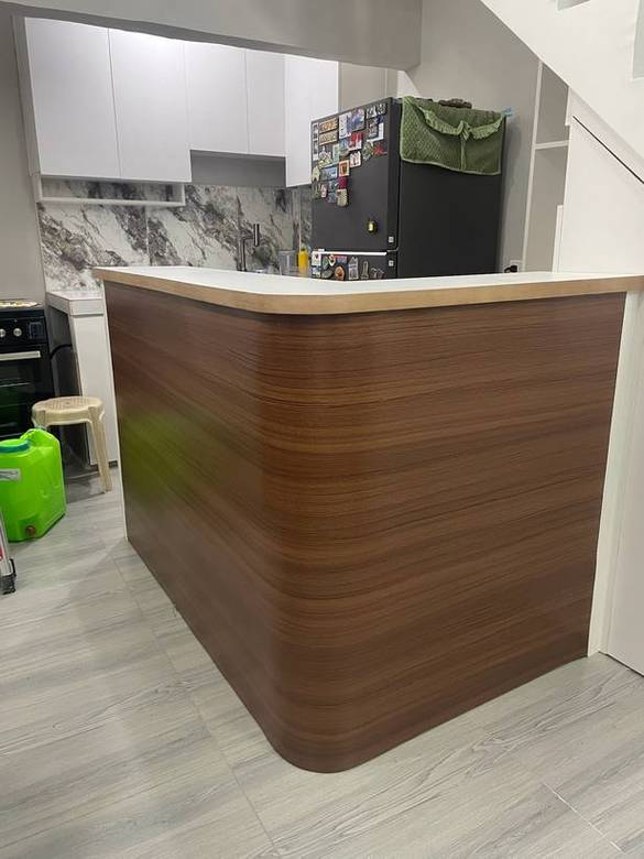 Curved walnut peninsula against white overheads, tucked under the stair