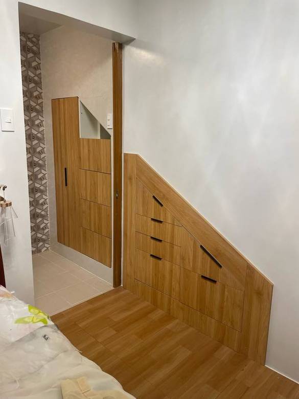 Storage wall with a concealed door and drawers cut to the stair line